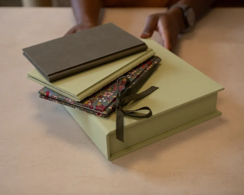 A stack of four notebooks tied with a black ribbon