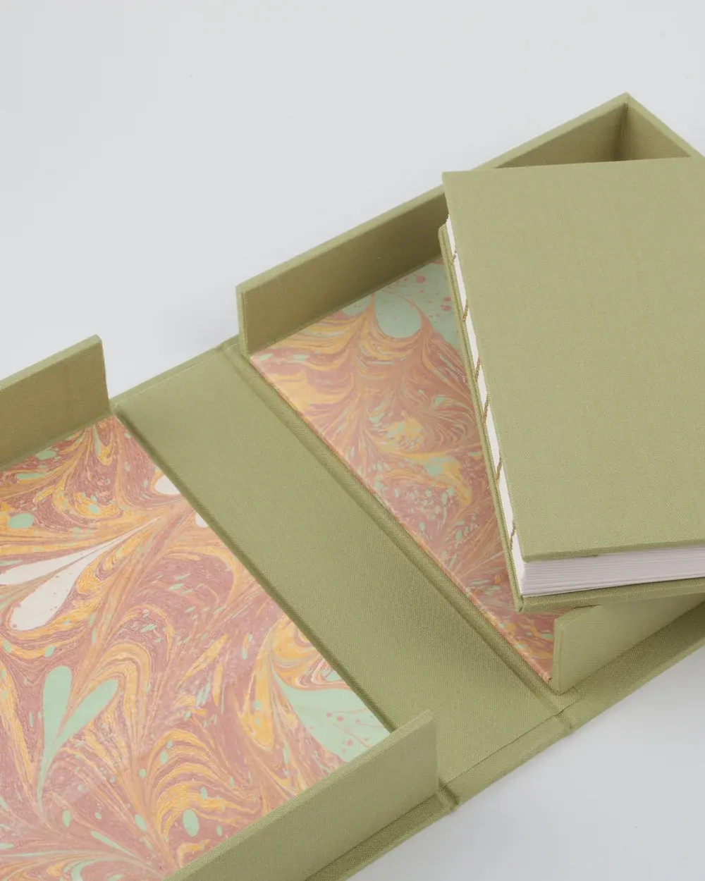 A lime green box with a marbled interior holding a spiral-bound book