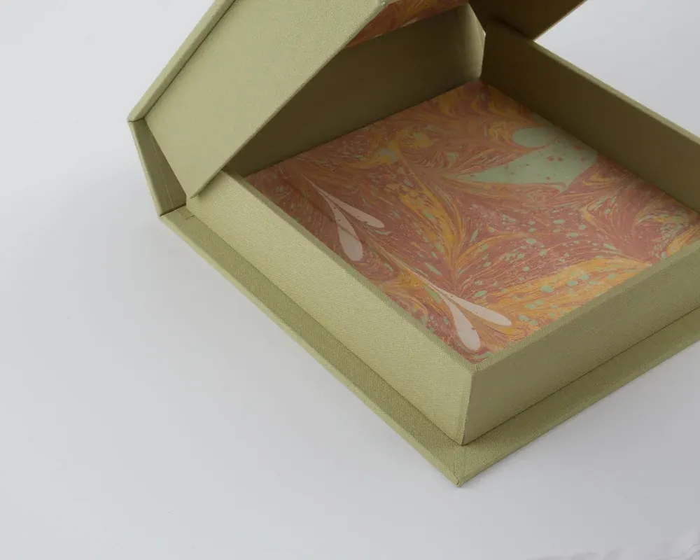 Open empty green box with textured exterior and marbled interior design.