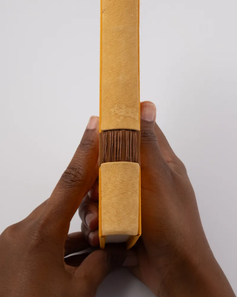 Person holding a book with a yellow cover, showing the spine and edges of the pages.