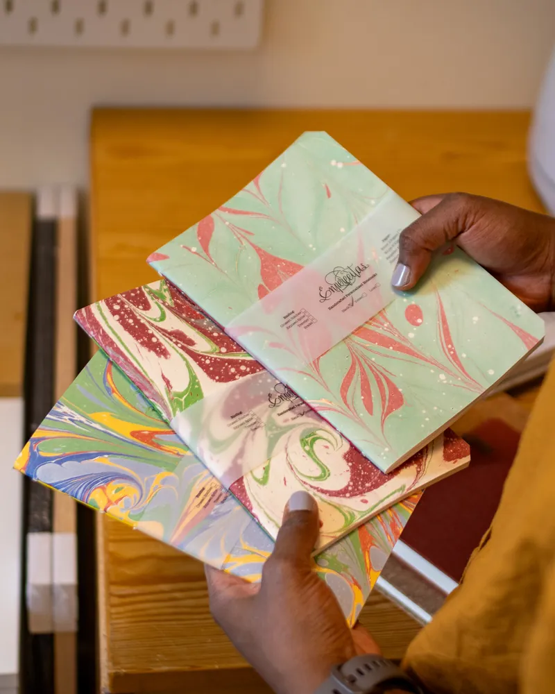 Person holding colorful marbled paper samples at a desk.