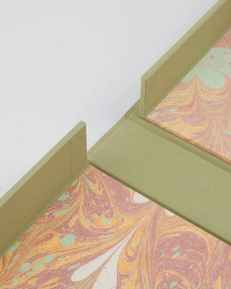 Close-up of a table with a marble-like top in pink, orange, and mint green swirl pattern and a light green fabric border.