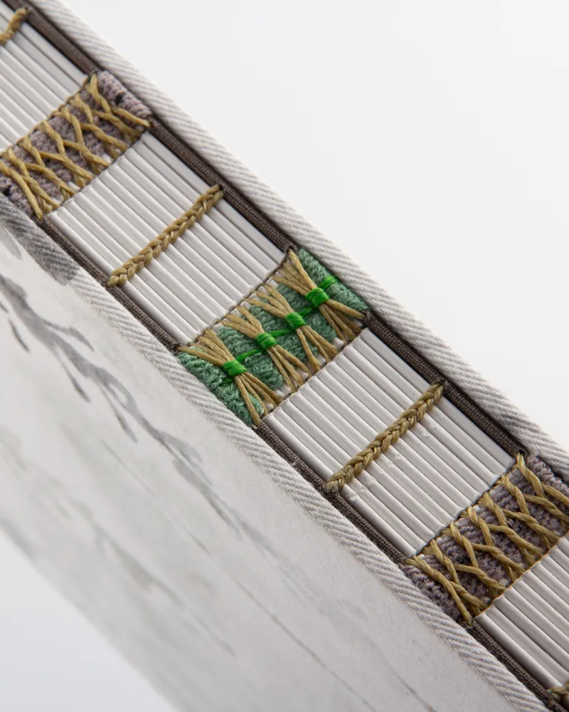 Close-up of a box spring with a zipper revealing neatly organized bed slats and decorative ropes inside.