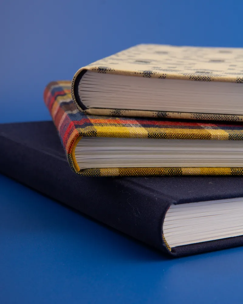 Stacked books with plaid fabric covers on a blue background.