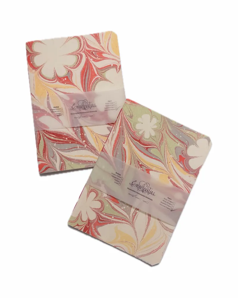 Two marbled notebooks with pastel colors and floral patterns, wrapped with translucent band labels that read 'Emperentas.'