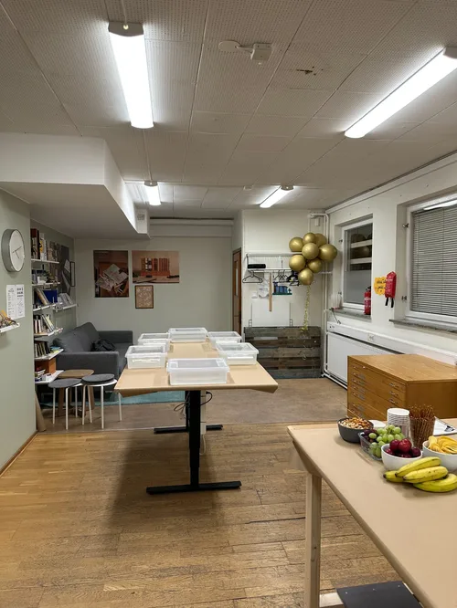 Indoor room with wooden floor, work tables and a bookshelf