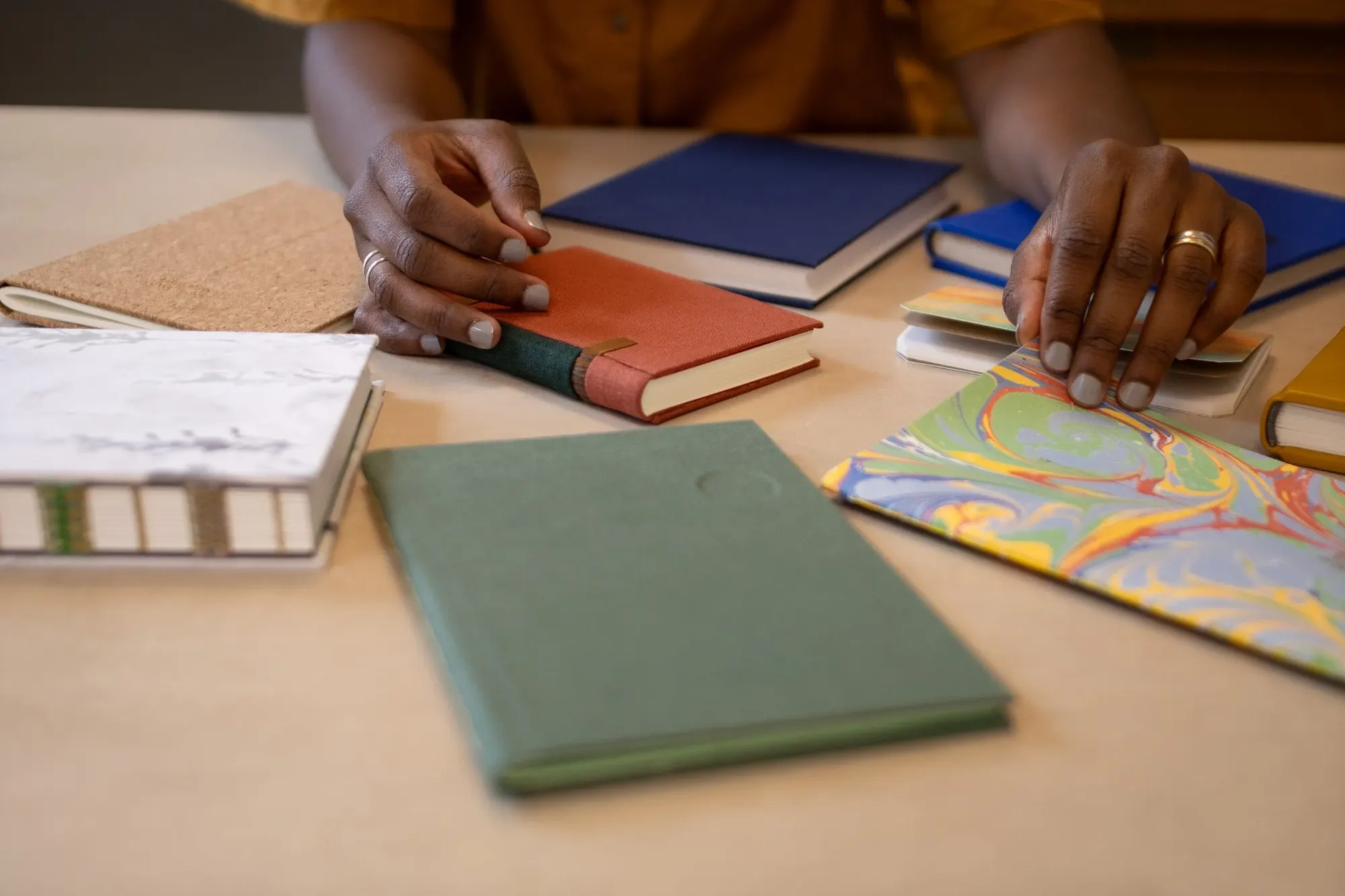 Hands arranging notebooks and marbled paper on a table